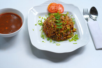 Sri Lankan Chicken Kottu with Gravy on White Plate with Spoon and Fork.