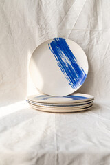 A set of handmade ceramic deep plates with a bowl like edge decorated with a striking cobalt oxide brush stroke
