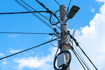 Concrete utility pole with electric cables, communication wires and LED street light against blue...