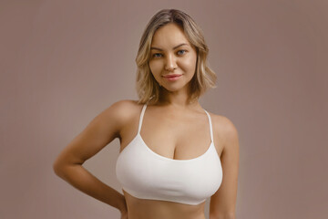 Fototapeta premium Beautiful blonde female in soft white underwear showing curvy, sensual figure. Healthy skin, sexy bust and confident attitude. Wellness, body care and femininity.