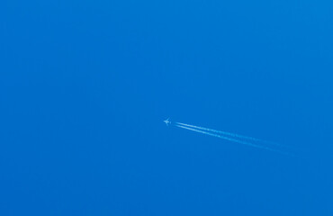 Commercial passenger airplanes cruising at high altitude on blue sky , view from a distance