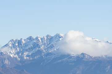 Fototapeta premium Veduta panoramica di cime innevate con soffici nuvole e un cielo azzuro pristino, Italia, Regione, Lombardia, Provincia di Lecco