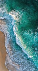 Aerial view of turquoise ocean waves crashing on a sandy beach, forming a foamy edge