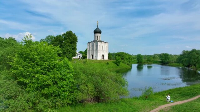 Bogolyubova, Russia - May 13, 2024: A view of the famous Church of the Intercession on the Nerl, a historic Russian Orthodox church situated by a river in a serene, green landscape