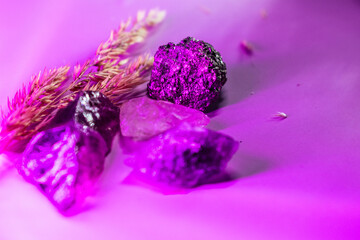 Raw amethyst and clear quartz crystals arranged with dried wheat on a purple surface, evoking...