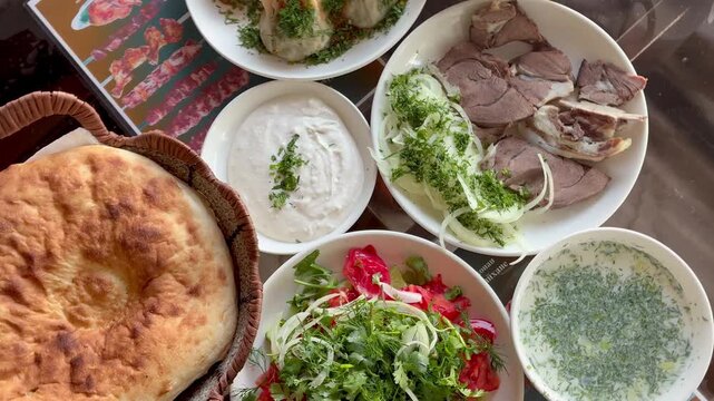 Top view of traditional Tajik food: manty, vegetable salad, boiled beef, non bread and Ayran