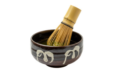 A matcha whisk inside a dark brown bowl with white designs, preparing a vibrant green matcha tea....