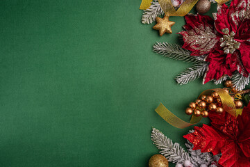 Festive red poinsettias, gold ornaments, and pine branches decorate the right side of a green background, leaving space for holiday text or design. Ideal for festive greeting cards, holiday banners