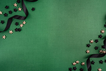 Chic black baubles, stars, and golden ribbon frame a green background, creating a bold and modern...
