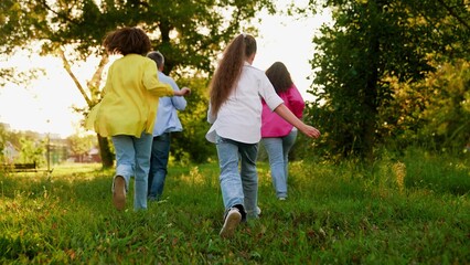 Fototapeta premium Happy young family, children parents running in park on lawn. Dad mom children girls having picnic in city park. Dad mom children daughters enjoying playing in nature park. Active recreation in nature