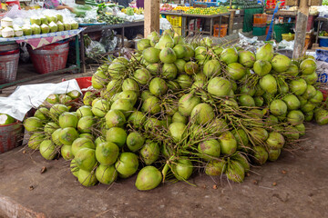 Fresh and colorful organic produce, including coconuts, are displayed on vibrant stalls in Thailand.