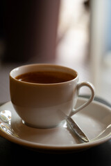 Hot Coffee Cup with Saucer and Spoon on Table in Cozy Cafe Atmosphere