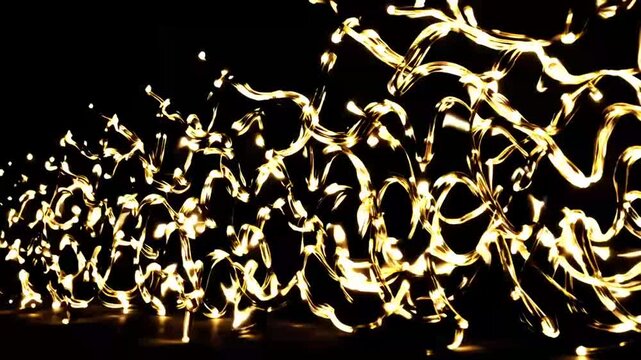 Long exposure graph capturing the swirling curves and waves of metallic gold fairy lights against black background gold