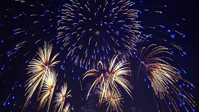 Pyrotechnic display of golden and azure sparks erupting in the nocturnal atmosphere to mark the commencement of new year
