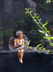 kleiner Bronzeengel vor einem Grabstein auf einem Friedhof in Würzburg