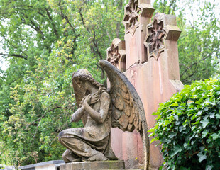 schöner alter Engel mit ausgebreiteten Flügeln kniet vor einem Grabstein auf dem Friedhof in Würzburg © Blende8
