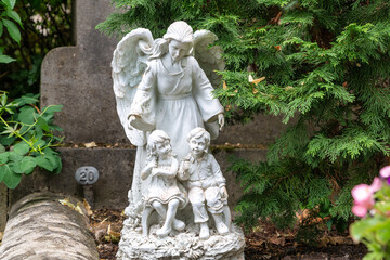 Obraz premium schöner großer Engel hinter zwei Kindern auf dem Friedhof in Würzburg