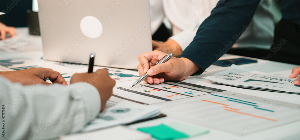Poster a dynamic business meeting featuring individuals engaging with charts and documents, demonstrating t