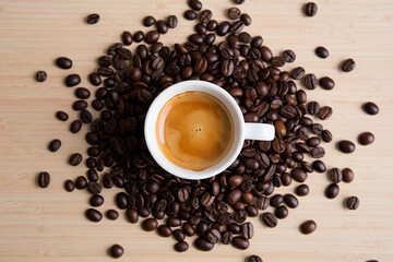Obraz premium Aromatic Espresso Cup Surrounded by Rich Coffee Beans on a Wooden Surface