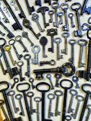 Old keys of different centuries, shapes, sizes, colors, materials are neatly laid out on gray...
