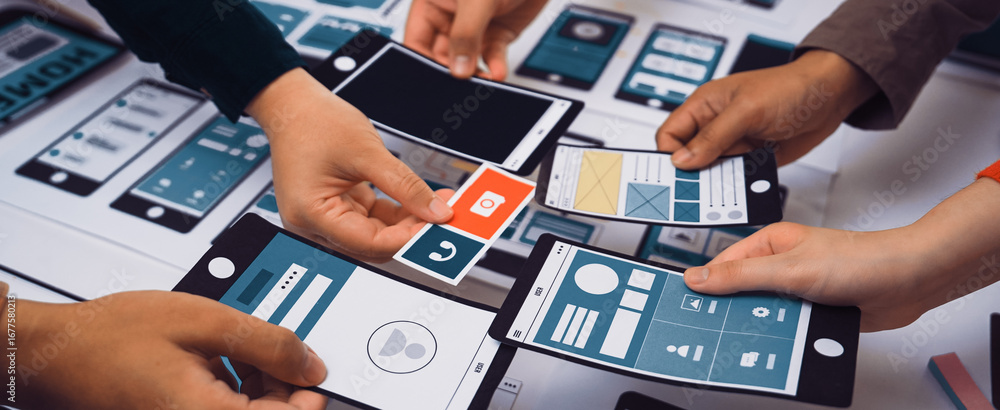 Poster hands are actively engaging with smartphone mockups and wireframes during a collaborative design ses