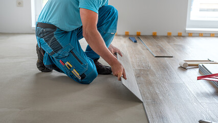 Floating floor work. The worker inserts the board of vinyl plank to the click system of Floating floor.