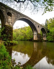 Fototapeta premium Ancient stone arch bridge over a calm river
