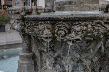Close up of historic stone fountain with sculpted animal heads spouting water in Göttingen, Germany