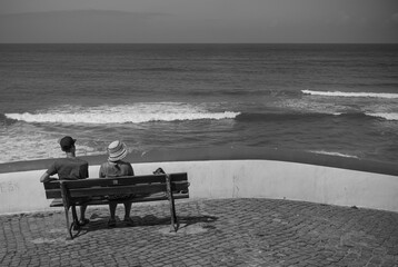 Couple sitting on a bench watching the sea