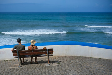 Couple sitting on a bench watching the sea