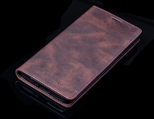 Leather phone case lying on black background with soft texture