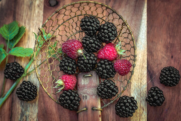 Blackberries and raspberries ready for cooking in a ladle on a wooden board