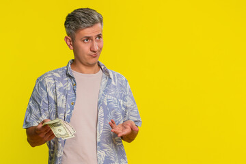 Middle-aged man pulling out few dollar bills from pocket spreading hands with helpless expression...
