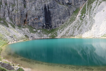 Naklejka premium Trentino, Italy - July 29, 2025: Panoramic view of the majestic Piz Boe and the surrounding Dolomite peaks, with lush green valleys and scattered snow, under a clear blue sky. beautiful view to Lake b