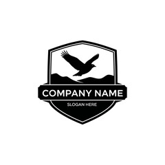 Black and white shield logo featuring a majestic eagle in flight over mountains, with a banner for company name and slogan.