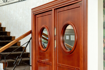 Classic wooden double swinging kitchen doors with round porthole windows in hotel restaurant...