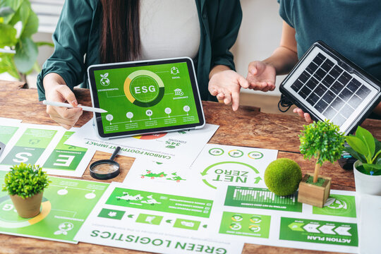 Business professionals discuss ESG sustainability strategy analyzing environmental data and green energy solutions for corporate responsibility