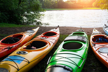 Close up seats colorful kayaks and paddles are prepared on the shore for a travel, tourism, and...