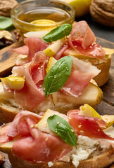Italian bruschetta with prosciutto, pear slices, cream cheese, fresh basil and sesame seeds.