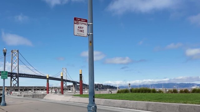 A street with a bridge in the background and a pole with a street light on it