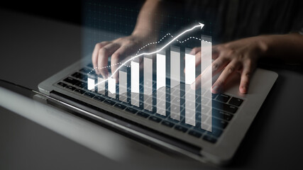 A focused workspace scene featuring hands typing on a laptop, with a digital overlay of a financial growth chart, symbolizing business success and data analysis. Impute