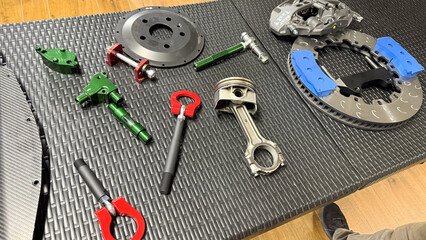 Automotive parts on workshop table, Top View: brake disc, ventilated rotor with blue segments,...