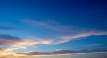 Obraz premium A peaceful evening sky unfolds with soft, colorful clouds illuminated by the setting sun, showcasing nature's tranquil beauty