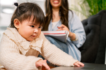 Baby girl reaching for laptop while mother works from home