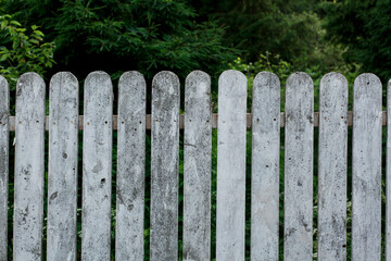 White wooden fence on the green summer garden forest background. front view