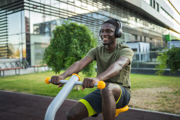 Young black sportsman exercising with stationary bike in a city park