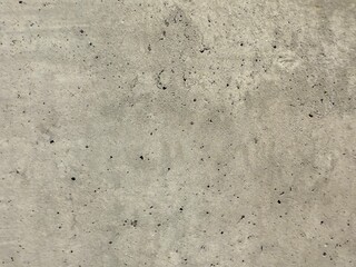 Fototapeta premium Close-up view of a concrete wall texture, showcasing its rough surface and industrial character. Ideal as a background for architecture, construction, or design projects needing a raw and urban.