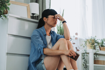 Depressed asian mature woman holding alcohol flask at home