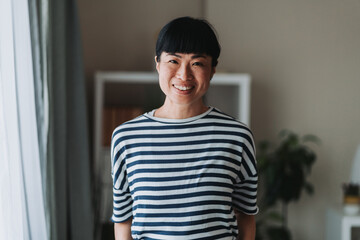 Portrait of smiling asian mature woman wearing striped shirt at home