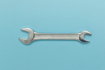 Minimalist Silver Wrench on Light Blue Background for Industrial and Repair Themes